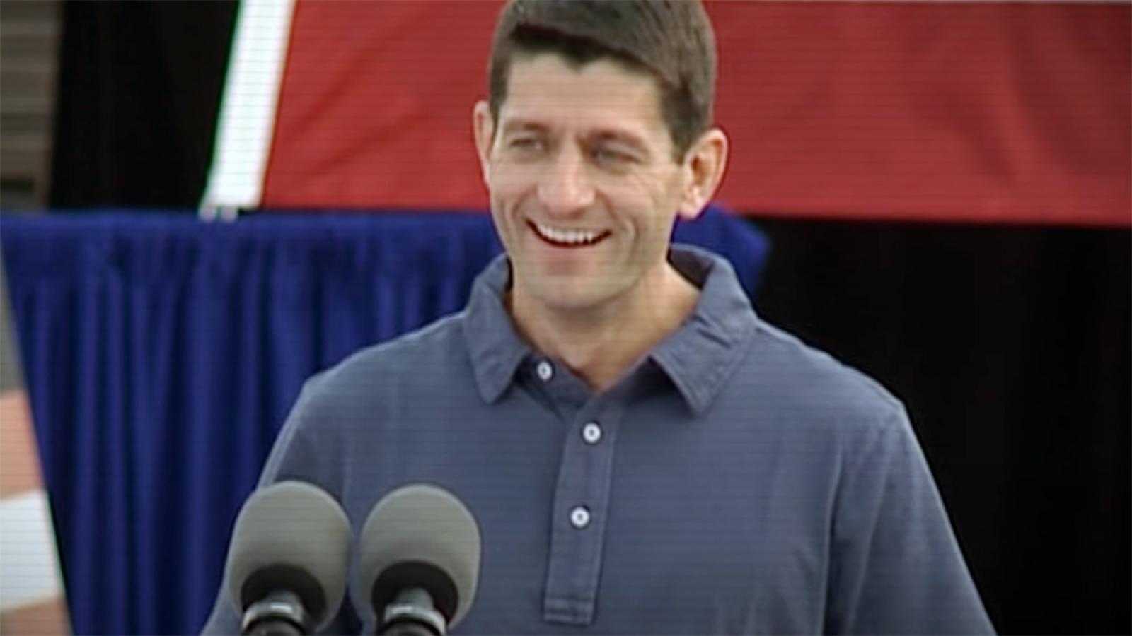 Paul Ryan standing behind two mics, smiling