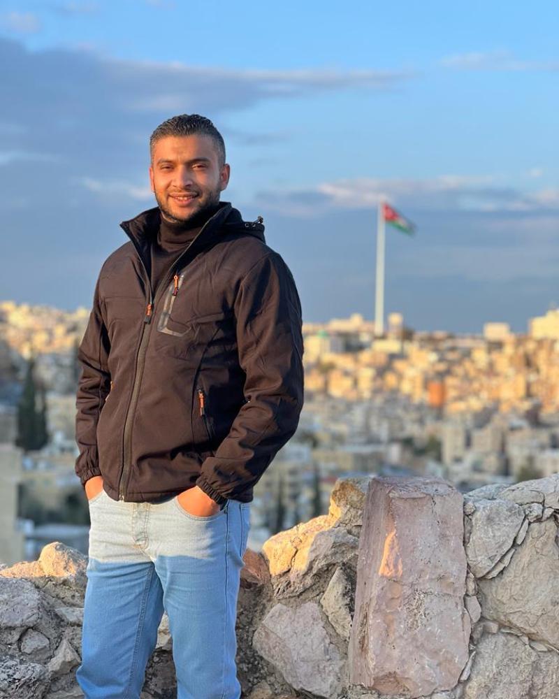 A man, Yousef, standing with a city landscape behind him.