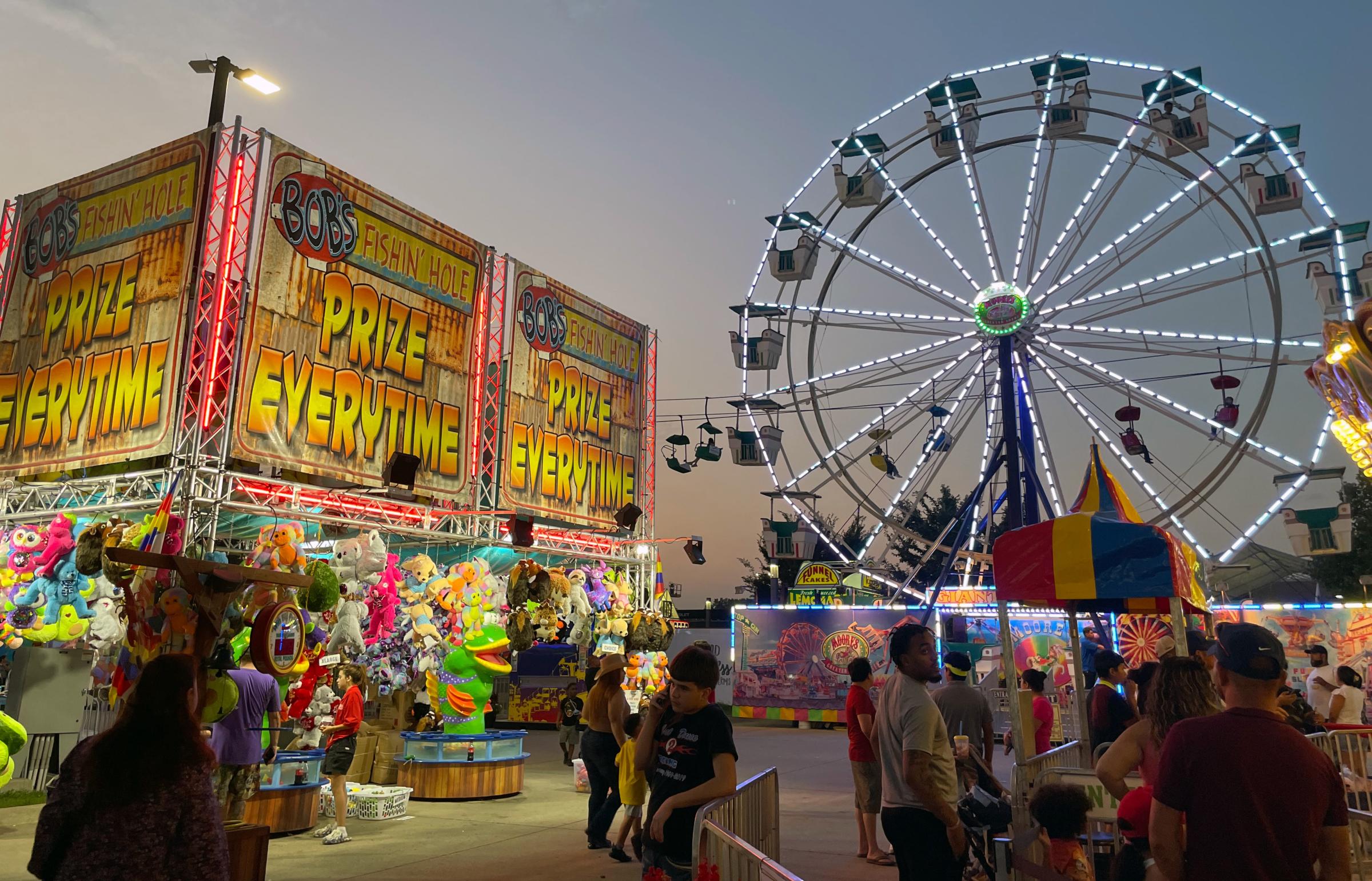 Photo of the Iowa State Fair featuring the ferris wheel and some games on the midway