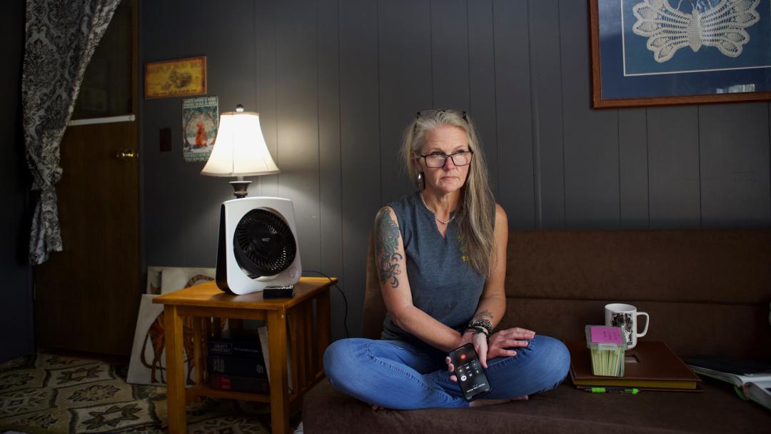 A photo of a woman siting on her couch holding a cell phone